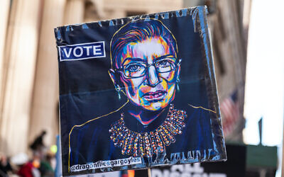 A protester holds up a sign with an image of the late Supreme Court Judge Ruth Bader Ginsburg as a few hundred demonstrators protest the Supreme Court nomination of Judge Amy Coney Barrett on Wall Street in New York City on October 17, 2020. (Photo by Gabriele Holtermann/Sipa USA)