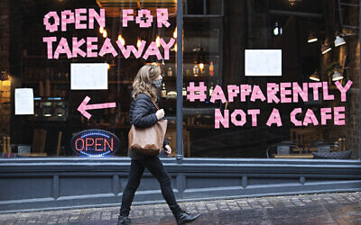 A woman walks past a cafe after a range of new restrictions to combat the rise in coronavirus cases came into place