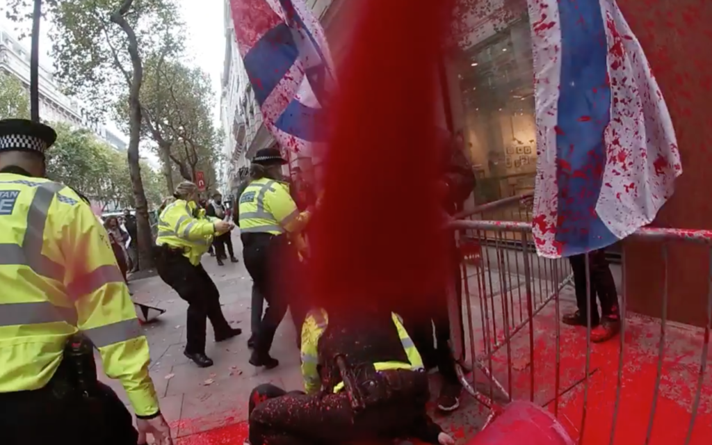 Police jump on demonstrators as they throw red paint on the building front of Elbit Systems, covering Israel activists in the substance in the process.
