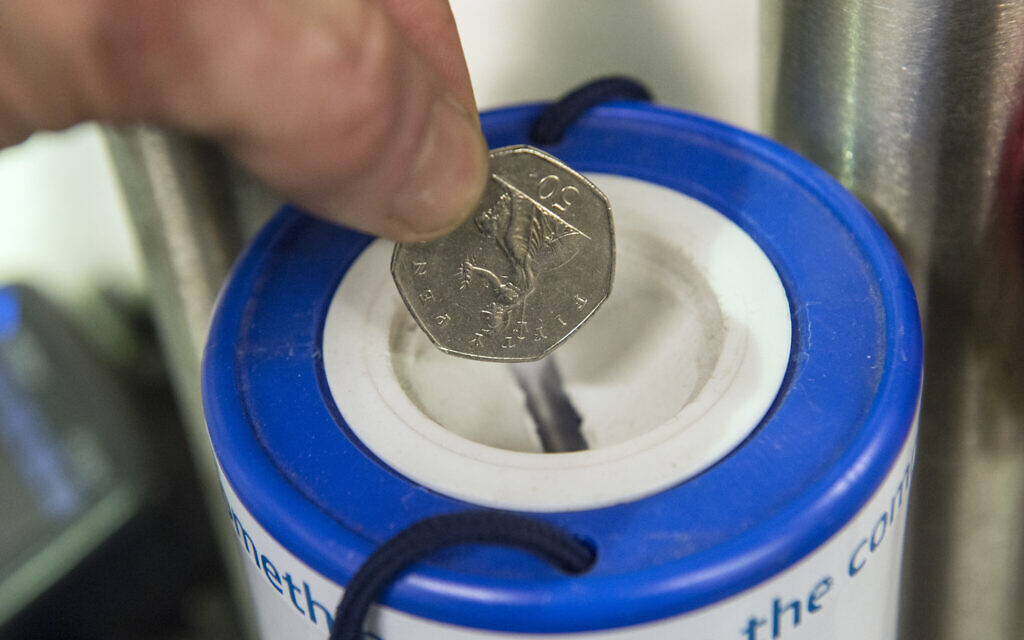 A coin is dropped into a charity collection container