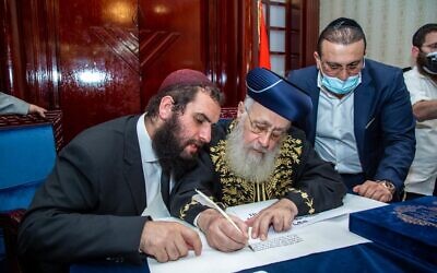 Chief Rabbi Yosef (centre) is joined by Rabbi Levi Duchman (left) as he signs a letter of endorsement for the community. 
  (Photo credit: Dubai Jewish Community Centre / Courtesy)