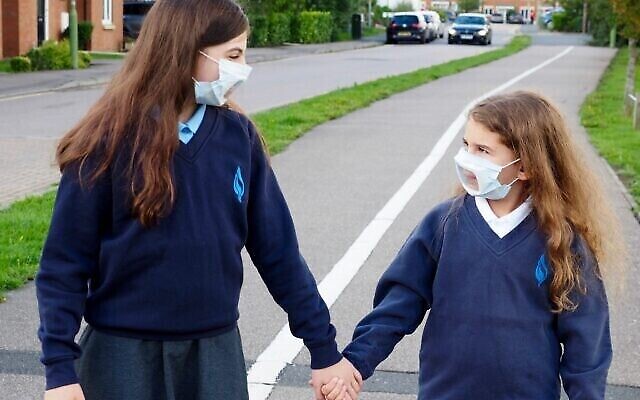 Sisters on their way to school with transparent face masks.