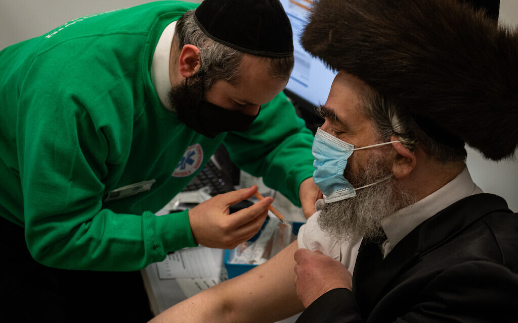 Strictly-Orthodox man receives his jab from a Jewish volunteer