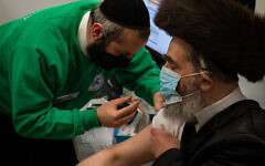 Strictly-Orthodox man receives his jab from a Jewish volunteer