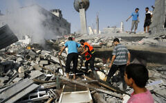 Palestinians extinguish a fire in a collapsed building, hit during an Israeli strike in the southern Gaza Strip in 2014.
  Photo by Abed Rahim Khatib/Pacific Press/ABACAPRESS.COM