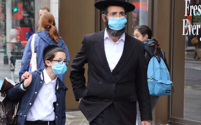 A Jewish man with his son walk along Oxford Street while while wearing face masks as a preventive measure against the spread of Coronavirus.
