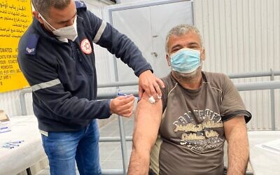 A Palestinian worker receives a shot of the Moderna vaccine from an Israeli paramedic (Photo: Magen David Adom)
