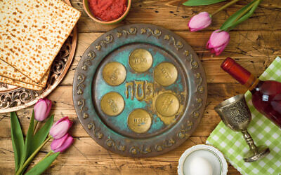 Jewish holiday Passover background with matzo, seder plate, wine and tulip flowers on wooden table. Top view from above.