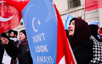 A woman seen shouting slogans while holding a placard during a protest against the Chinese policies in Xinjiang.