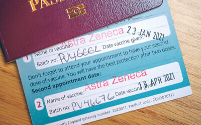 Vaccine certificate issued by NHS UK with second Astra Zeneca vaccination stamped, certificate tucked inside UK passport. Credit: Malcolm Park/Alamy Live News.