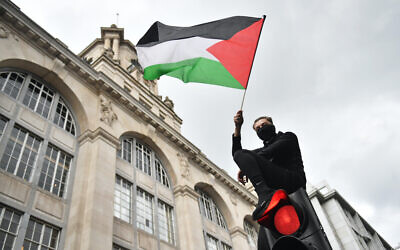 A demonstrator waves a Palestinian flag whilst sat atop a traffic light in London, during a march in solidarity with the people of Palestine amid the ongoing conflict with Israel. Picture date: Saturday May 15, 2021.