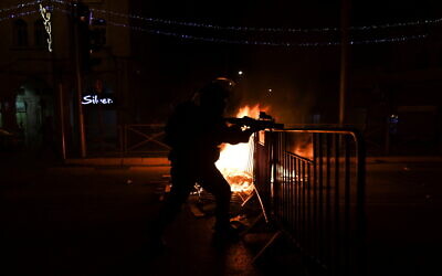 An Israeli policeman next to a burning barricade during clashes with Palestinians on Saturday night in Jerusalem's Old City, May 8, 2021. (Photo: Reuters/Ronen Zvulun)