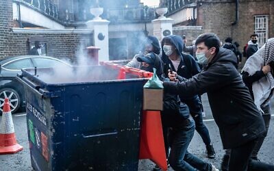 Rioters push a recycling bin towards police during the demonstration.