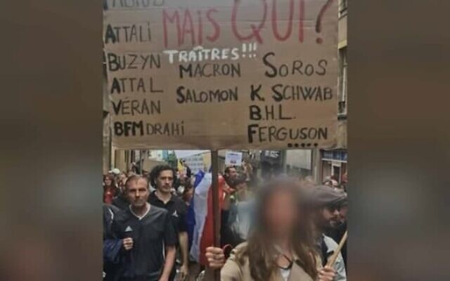 A woman holds up a placard denouncing President Emmanuel Macron and several prominent Jews denounced as traitors at a protest against COVID restrictions in Metz, France on Aug. 7, 2021. (Gérald Darmanin/Twitter) via JTA