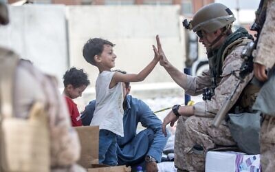 A U.S. Marine with the Special Purpose Marine Air-Ground Task Force-Crisis Response team, high fives a child waiting for evacuation at Hamid Karzai International Airport during Operation Allies Refuge August 22, 2021 in Kabul, Afghanistan.
