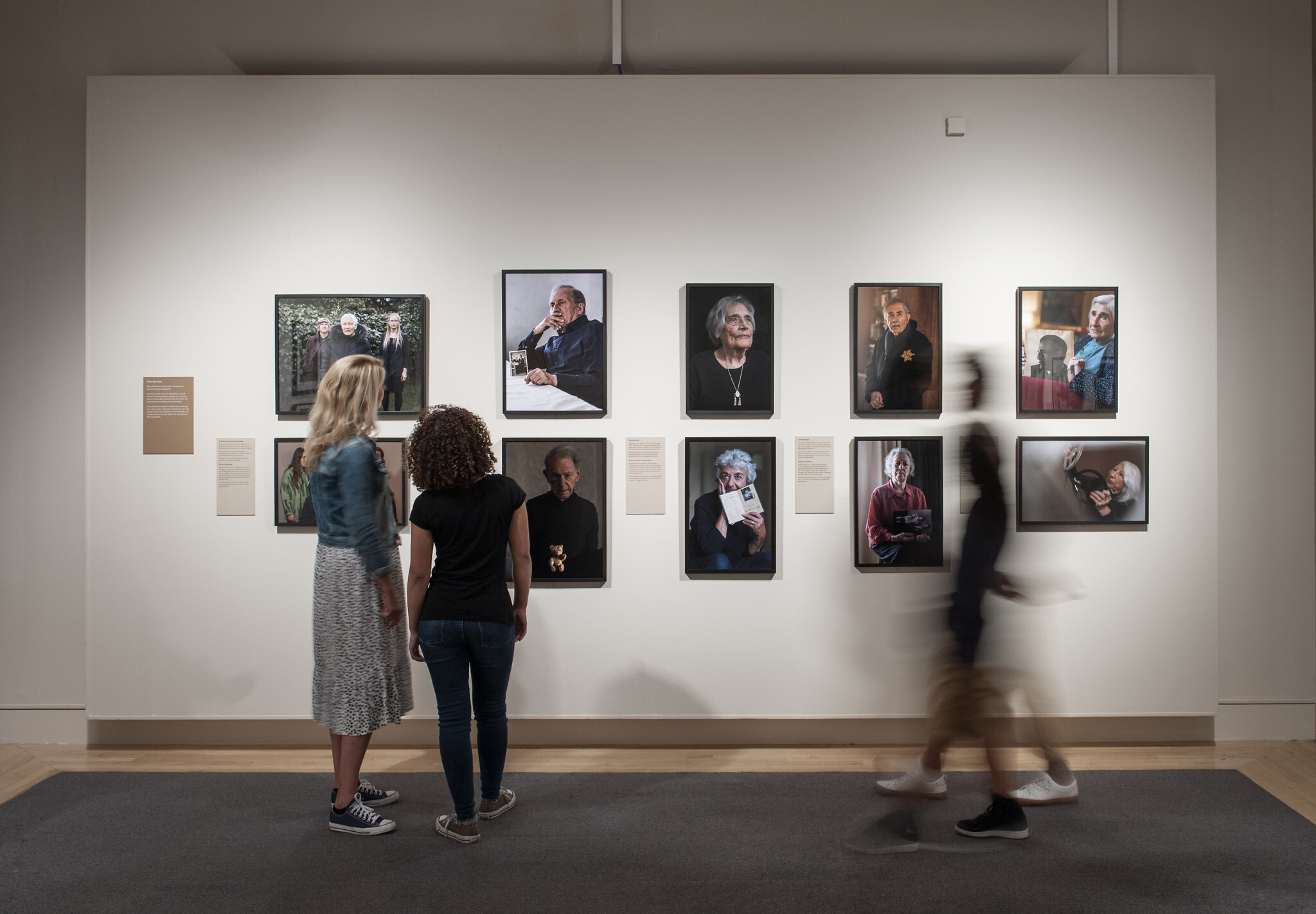 Visitors explore Generations: Portraits of Holocaust Survivors at IWM London. © IWM