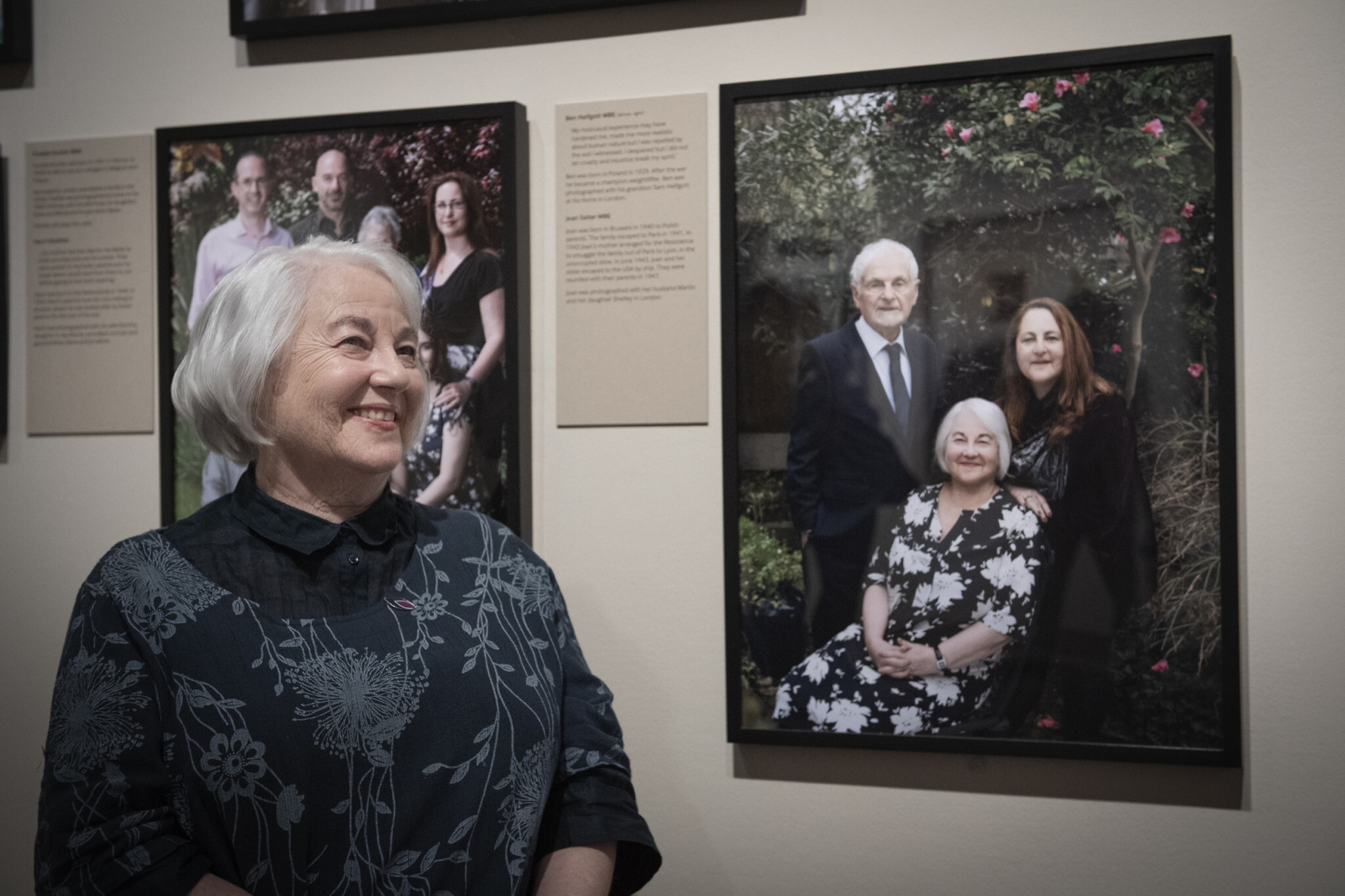 Joan Salter MBE sits alongside her portrait by Frederic Aranda, exhibited at IWM London as part of Generations: Portraits of Holocaust Survivors.© IWM