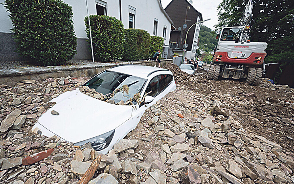 A car is buried by rubble in the Hohenlimburg district. Credit: Julian Stratenschulte/dpa/Alamy Live News