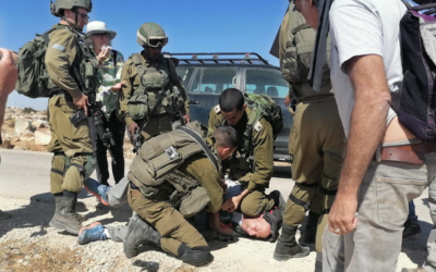 An IDF officer kneels on the neck of activist Tuly Flint in the West Bank on Sept. 17, 2021. (Courtesy of Combatants for Peace)