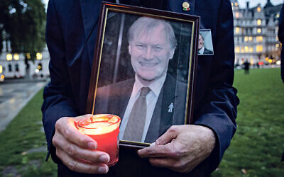 A woman holds a framed picture of Sir David Amess with a candle (Photo by Tejas Sandhu / SOPA Images/Sipa USA)