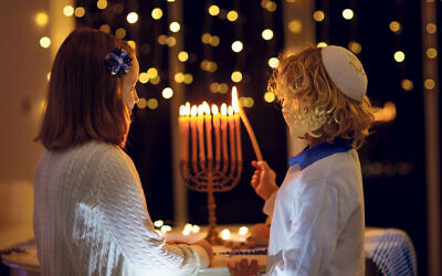 Children lighting Chanukah candles on traditional menorah