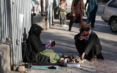 Hadia Ahmadi, 43, a teacher in various schools until the Taliban took control, now waxes shoes for people along a street in Kabul (Photo: Reuters/Ali Khara)