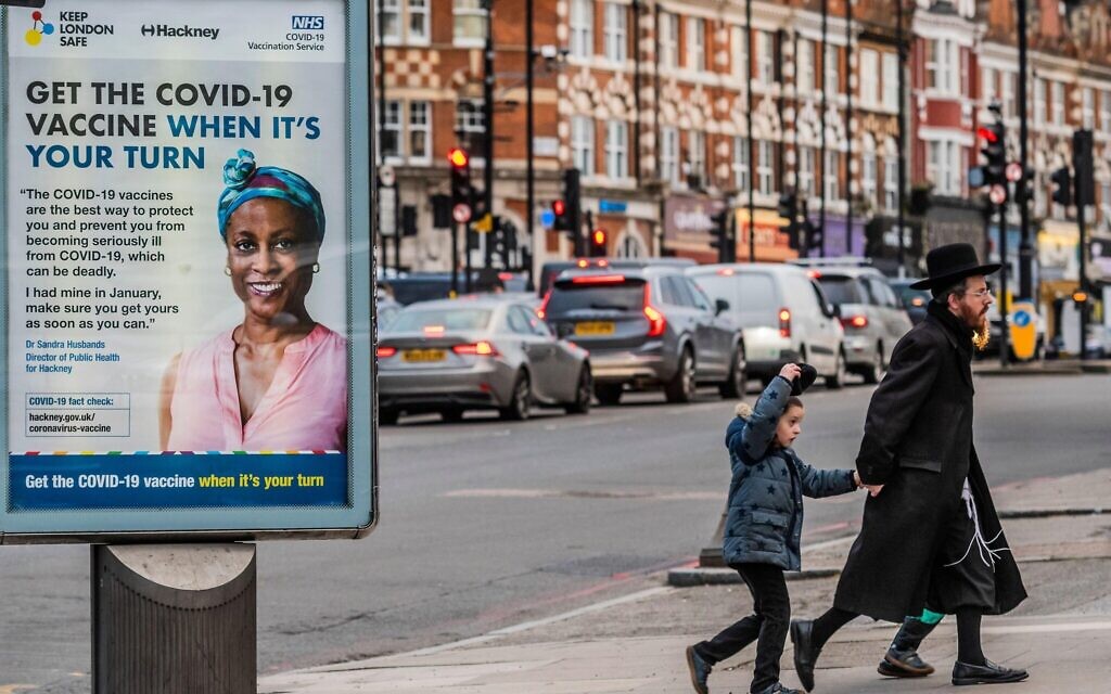 Orthodox Jewish people pass government covid information signs (get the vaccine when its your turn) as they prepare for Purim in Stamford Hill,   Credit: Guy Bell/Alamy Live News
