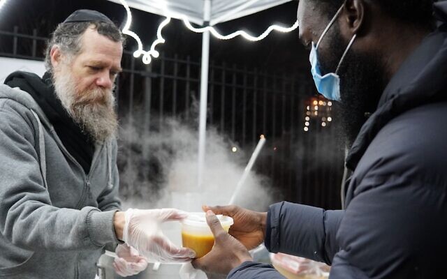 A volunteer, left, distributes hot soup at a distribution tent set up by the Masbia kosher pantry network near the scene of a deadly fire in the Bronx, Jan. 10, 2022. The fire, which claimed 19 lives, is the city's deadliest in 30 years. (Courtesy Masbia) via JTA