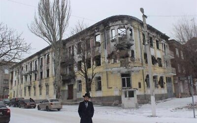 Cohen stands outside of the burned out building that served as local police headquarters. (Chabad.org)