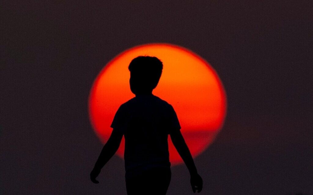 2JHHAGT London, UK.  18 July 2022.  UK Weather ? A boy views the sunset at Northala Fields near Northolt in west London on a day when temperatures rose to 38C.  The UK Health Security Agency (UKHSA) has increased its heat health warning to level 4, a ?national emergency? and the Met Office has issued its first red warning for much of England with temperatures expected to rise to 41C tomorrow. Credit: Stephen Chung / Alamy Live News