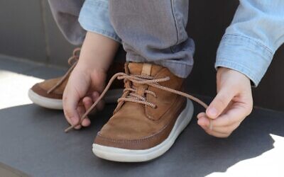 Little boy tying shoe laces on stairs outdoors, closeup