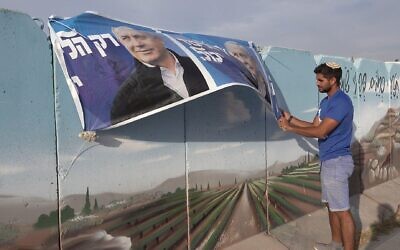 An Israeli man hangs an election campaign banner for the Likud party depicting its leader Benjamin Netanyahu on October 19, 2022, near the Palestinian town of Hawara, south of Nablus, West Bank. Credit: Eddie Gerald/Alamy Live News