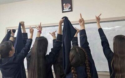 Protesting Iranian school girls raise their middle fingers – an obscene gesture – at the portraits of Ayatollah Khamenei and the founder of the Islamic Republic, Ayatollah Ruhollah Khomeini.