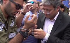 A right wing activist dressed in military uniform has his handcuffs unlocked by extreme Right-wing lawmaker Itamar Ben-Gvir, head of the Otzma Yehudit political party, as a symbol of easing the army's policy against Palestinians