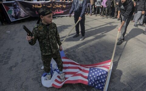 A Palestinian child, holding what appears to be a toy gun, tramples on the flags of Israel and America before burning them during a demonstration in the Jabalia camp in the northern Gaza Strip, in support of the Jenin camp in the West Bank, on January 27. 2023.