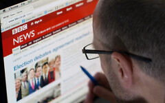 A man looking at the website of bbc news on desktop computer