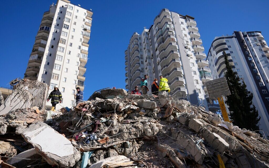 Emergency teams search for people in the rubble of a destroyed building in Adana, southern Turkey, Tuesday, Feb. 7, 2023. A powerful earthquake hit southeast Turkey and Syria early Monday, toppling hundreds of buildings and killing and injuring thousands of people. (AP Photo/Hussein Malla)