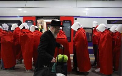 An ultra Orthodox Jewish man walks past women wearing costumes from the TV series 'The Handmaid's Tale' during an anti-government protest at a train station in Jerusalem, Israel, 01 March 2023. People have been protesting all over the country against the government’s justice system reform. EPA-EFE/ABIR SULTAN