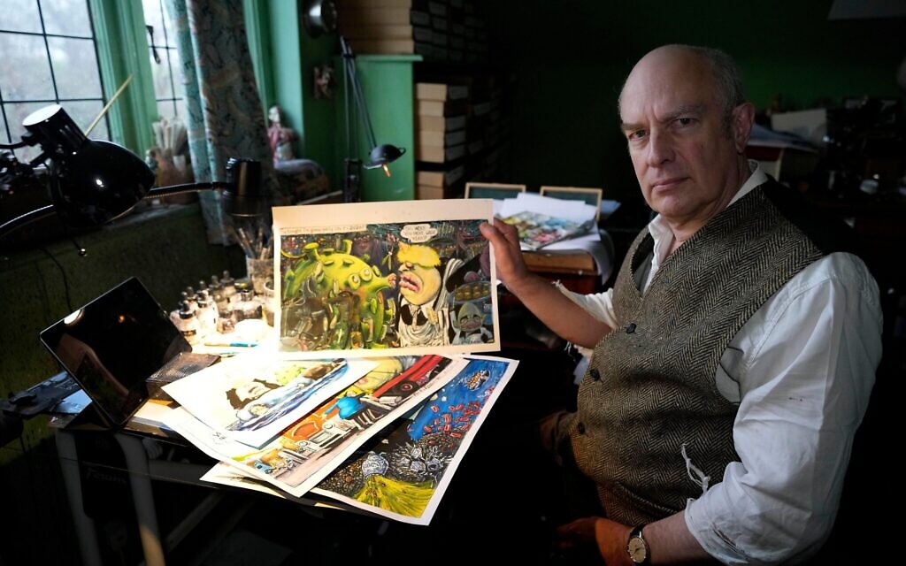 Martin Rowson shows Britain's Prime Minister Boris Johnson cartoons as he poses for a photographer in his studio in London, Monday, Jan. 24, 2022. (AP Photo/Frank Augstein)