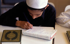 A child writing in an exercise book in a classroom, Saudi Arabia. A child writing in an exercise book in a classroom, Saudi Arabia.