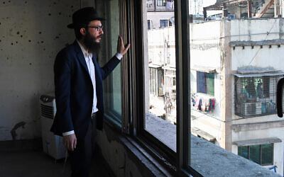 Rabbi Israel Kozlovsky, director of Mumbai's Chabad center, looks out of a window of the center, in front of a wall pock-marked with bullet holes from the 2008 terror attack. (Ashish Vaishnav/SOPA Images/LightRocket via Getty Images)