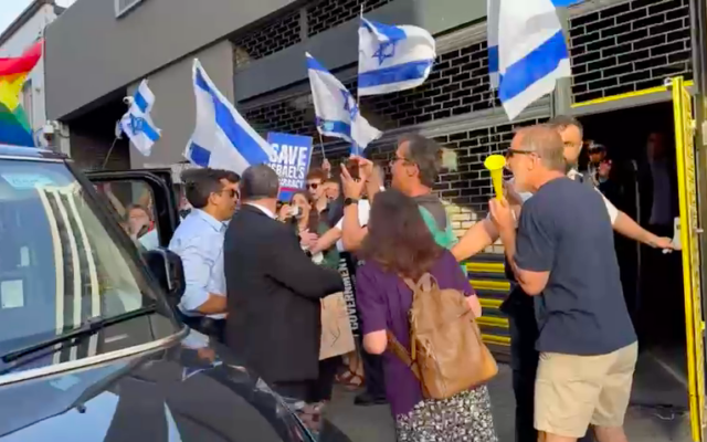 Protesters greet Israeli minister Amichai Chikli (white shirt) in London as he arrives at meeting at Jewish Agency HQ  in north London