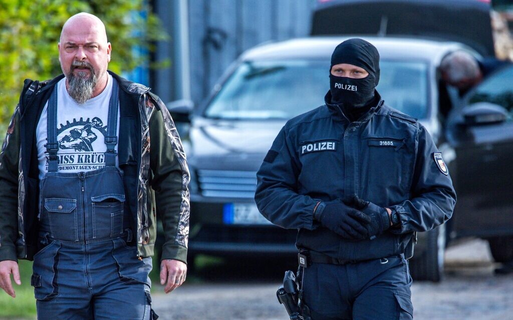 19 September 2023, Mecklenburg-Western Pomerania, Jamel: Sven Krüger (l), a right-wing extremist known throughout Germany, is accompanied by a police officer during a search operation on his property. Federal Interior Minister Faeser has banned the right-wing extremist association "Hammerskins Germany" as well as its regional offshoots and the sub-organization "Crew 38". According to the ministry, police task forces searched the homes of 28 suspected members of the association in ten German states in the early morning. Photo: Jens Büttner/dpa (Photo by Jens Büttner/picture alliance via Getty Images)