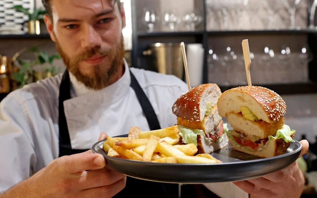 Israeli chef Shachar Yogev serves a burger made with "cultured chicken" meat at The Chicken, SuperMeat's restaurant adjacent to their production site in the Israeli town of Ness Ziona on June 18, 2021. (Photo by JACK GUEZ/AFP via Getty Images)