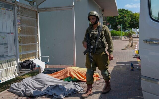 An Israeli soldier stands by the bodies of Israelis killed by Palestinian armed militants who entered from the Gaza Strip,
