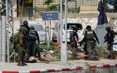 Israeli police station stands by the bodies of militants outside the police station that was overrun by Hamas gunmen on Saturday, in Sderot, Israel, Sunday, Oct.8, 2023. Hamas militants stormed over the border fence Saturday, killing hundreds of Israelis in surrounding communities. (AP Photo/Ohad Zwigenberg)