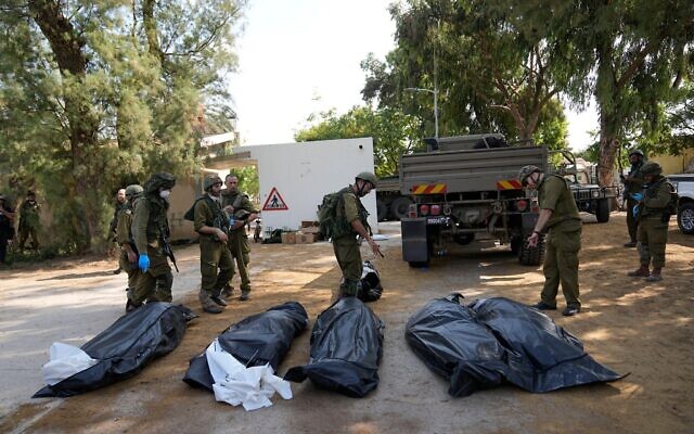 Israeli soldiers stand next to the bodies of Israelis killed by Hamas terrorists in kibbutz Kfar Azza on Tuesday, Oct. 10, 2023. Hamas militants overran Kfar Azza on Saturday, where many Israelis were killed and taken captive. (AP Photo/Ohad Zwigenberg)
