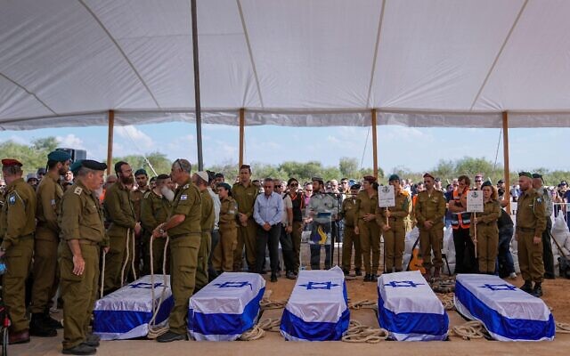 Mourners gather around the five coffins of the Kotz family during their funeral in Gan Yavne.