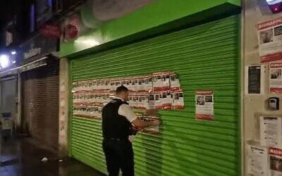 Video on social media showed two officers standing outside Cullimore Chemist in Edgware, stripping posters of hostages taken by Hamas