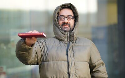 Urslaan Khan, holds up a copy of The Genius of Dickens by Professor Michael Slater, as he leaves Westminster Magistrates Court, London, where he appeared charged with supporting Hamas during a Downing Street protest. Khan, 41, from east London, is accused of expressing an opinion supportive of the proscribed terrorist organisation on October 17.
